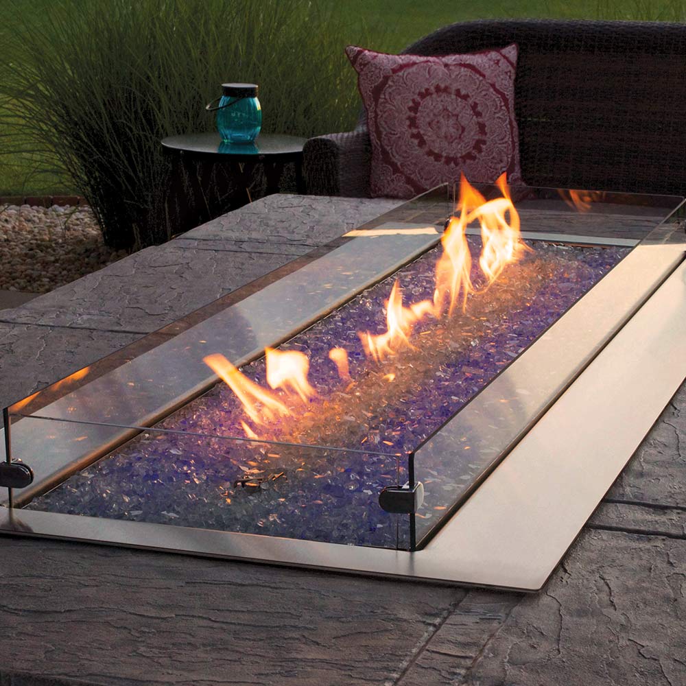 Outdoor linear gas fire pit with blue LED glow and flames across glass panel