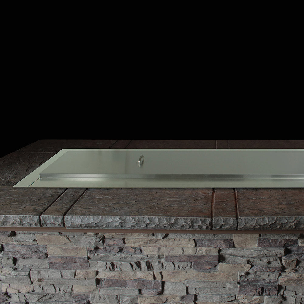 Linear gas fire pit burner tray set into stone surround on patio