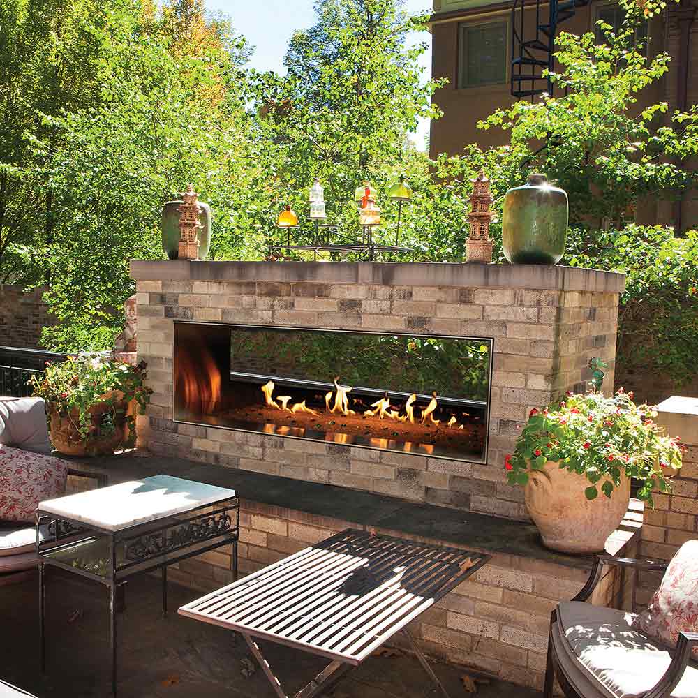Outdoor stone see-through gas fireplace with glowing flame bed and LED highlights