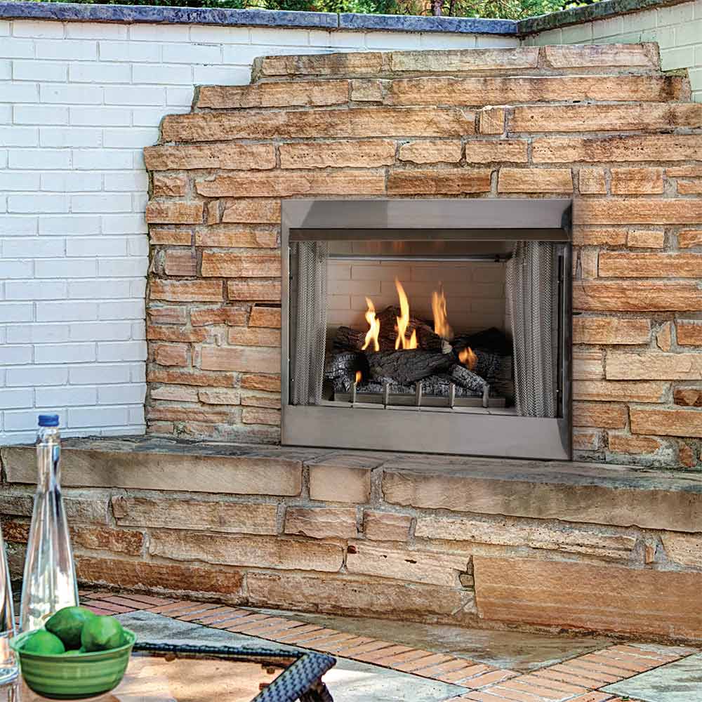 Outdoor gas fireplace in a stone wall niche, stainless frame with burning logs