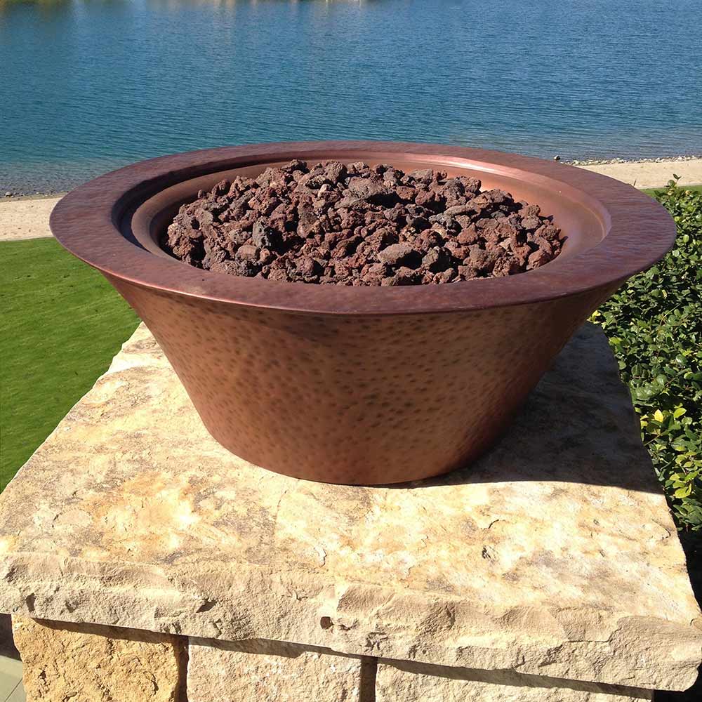 Round copper gas fire bowl filled with black fire rocks, no flames