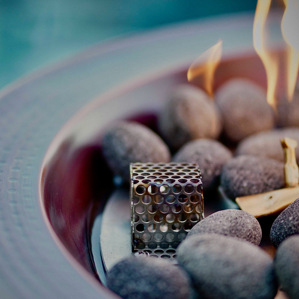 Copper gas fire bowl interior with flames and gray lava rocks