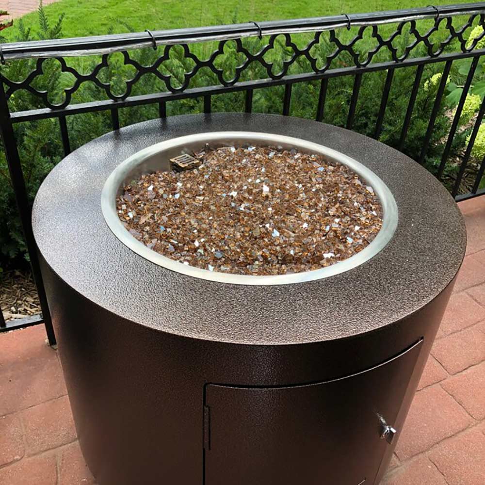 Round gas fire pit with dark powder-coated steel body and burner pan filled with fuel