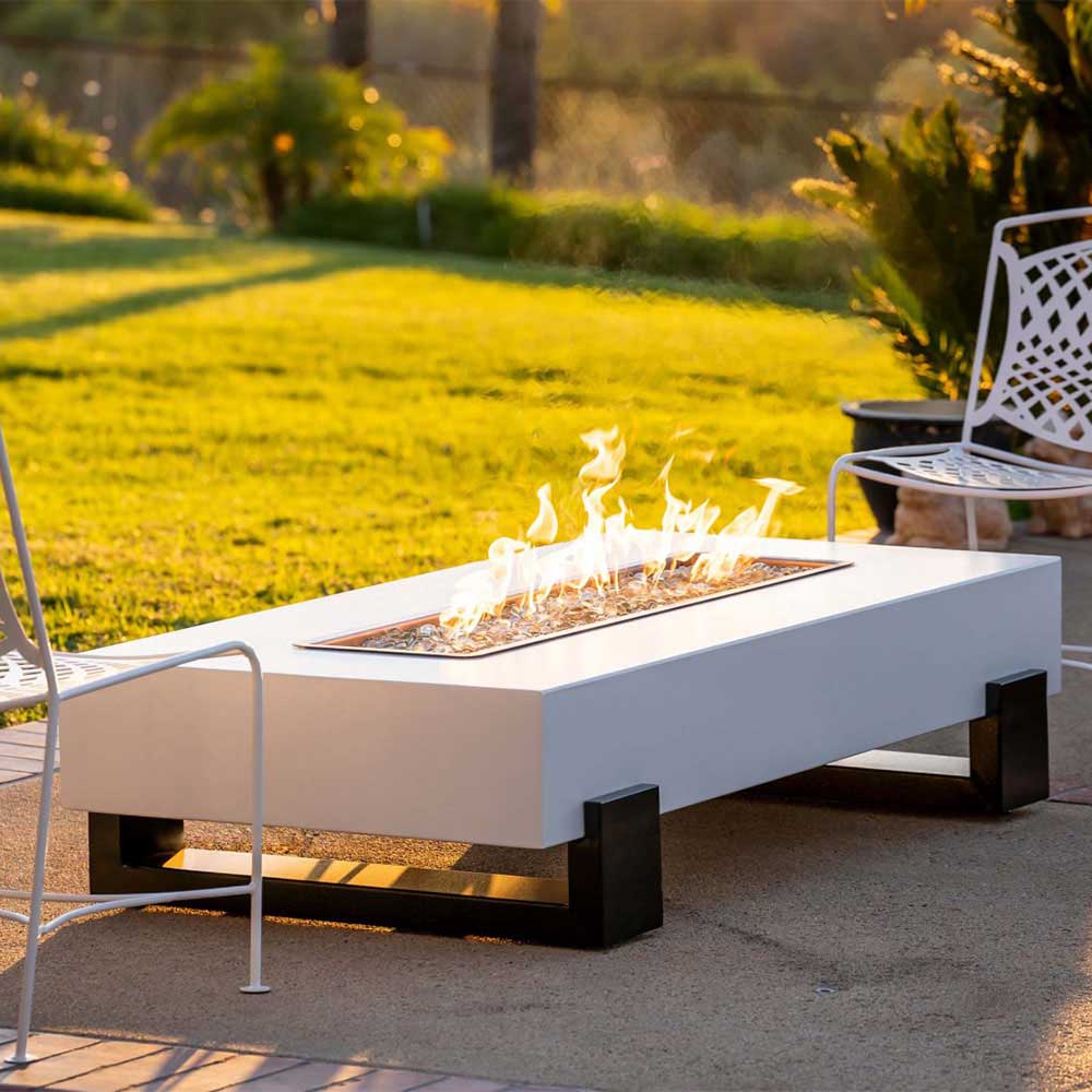Outdoor gas fire pit with white rectangular firebox, black legs, burning flames
