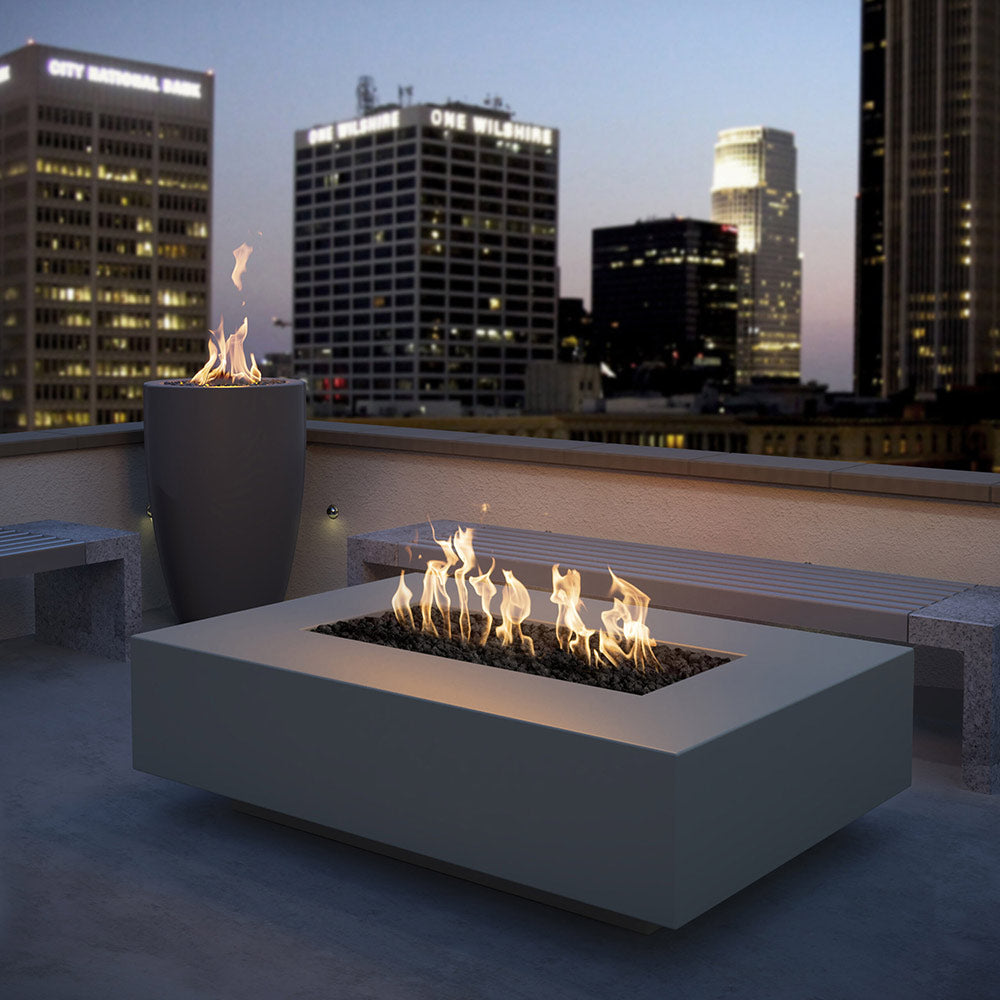Outdoor linear concrete gas fire pit with dark finish and visible flames in burner tray.