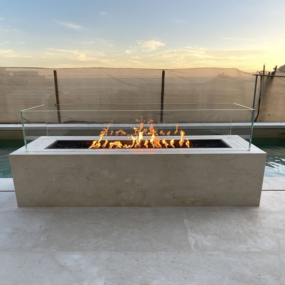 Outdoor linear concrete gas fire pit with light finish and flames burning inside tray.