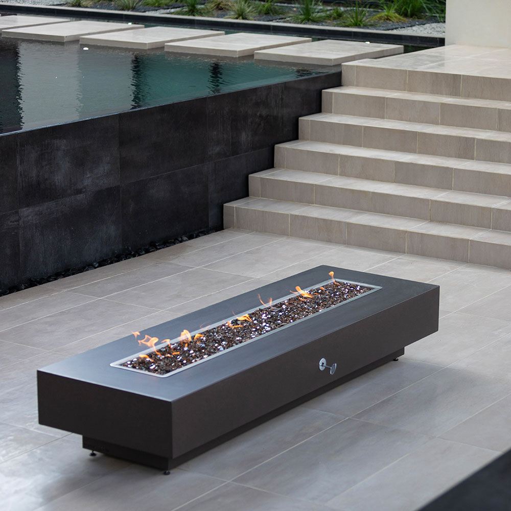 Dark gray linear gas fire pit with flames in long rectangular burner pan