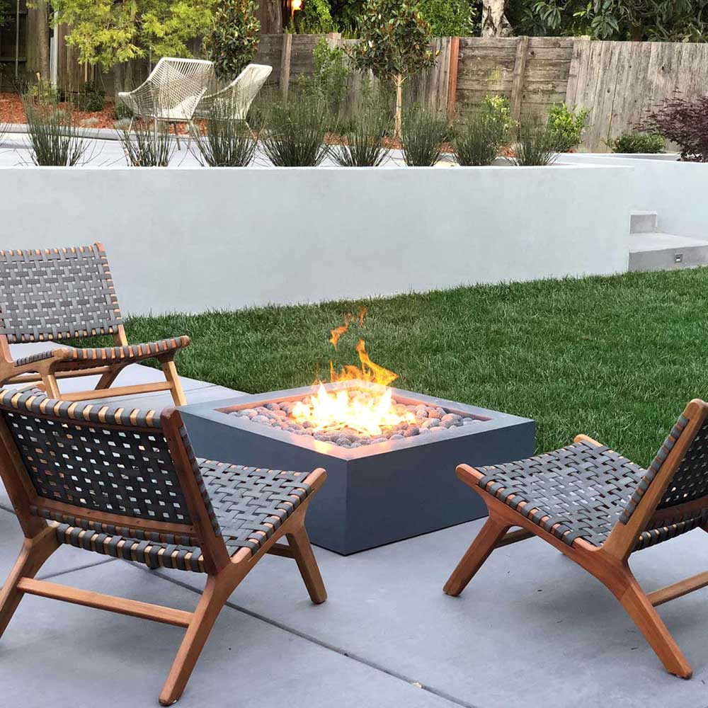 Dark gray square concrete gas fire pit with flames in the center burner tray