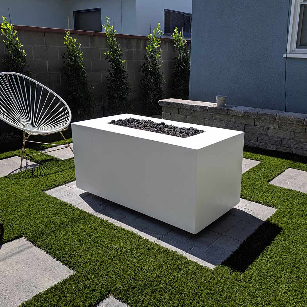 Gas fire pit with white rectangular body, black burner tray, and visible flames
