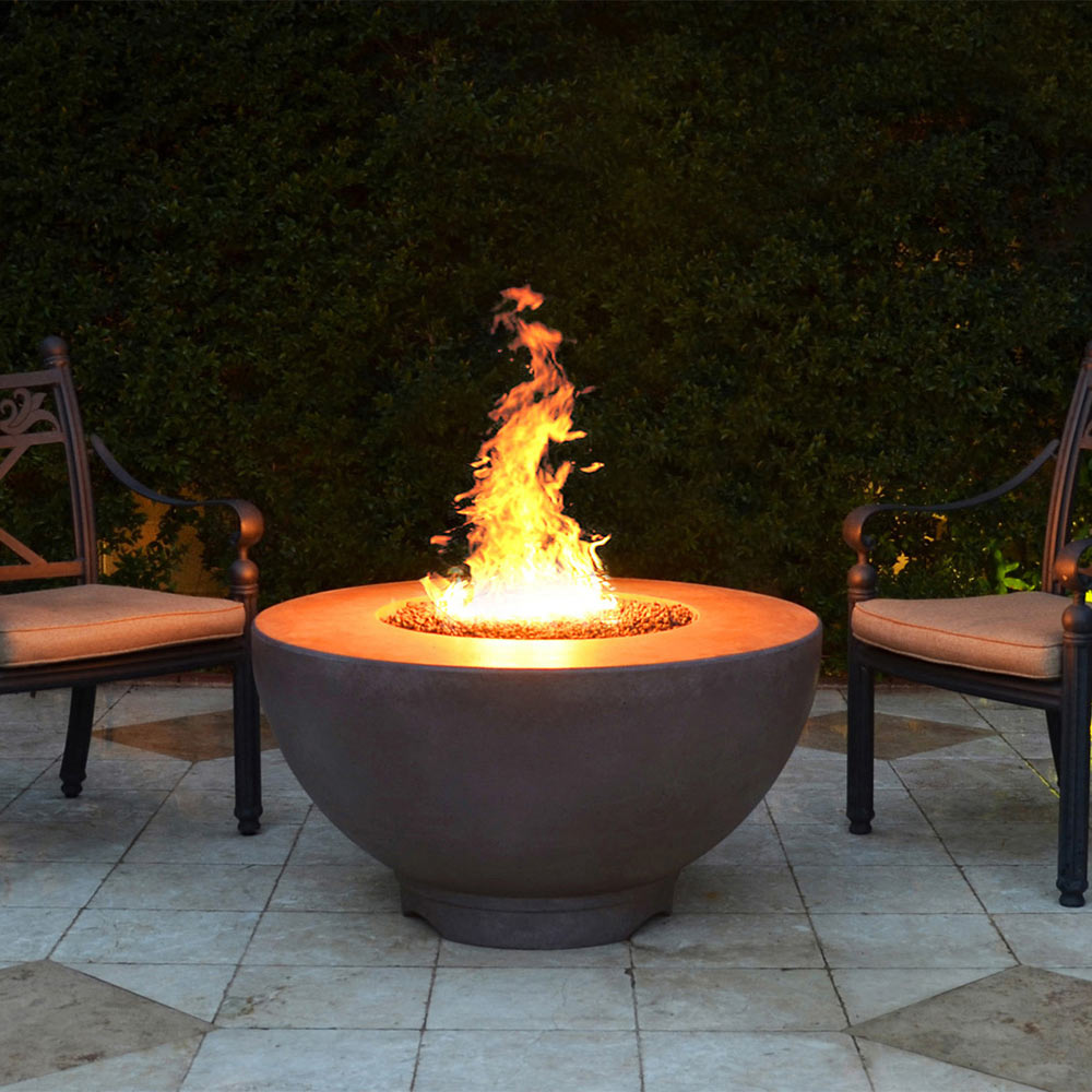 Gray round concrete gas fire pit with tall flame burning in center