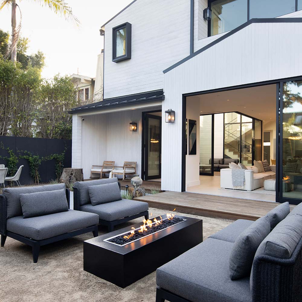 Outdoor patio with black linear concrete gas fire pit burning