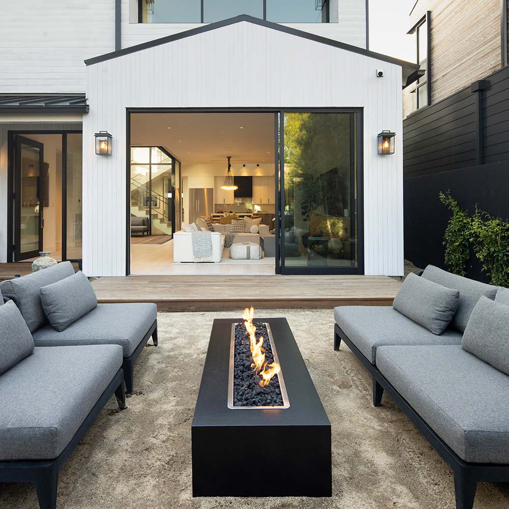 Black linear concrete gas fire pit with flames in the burner channel