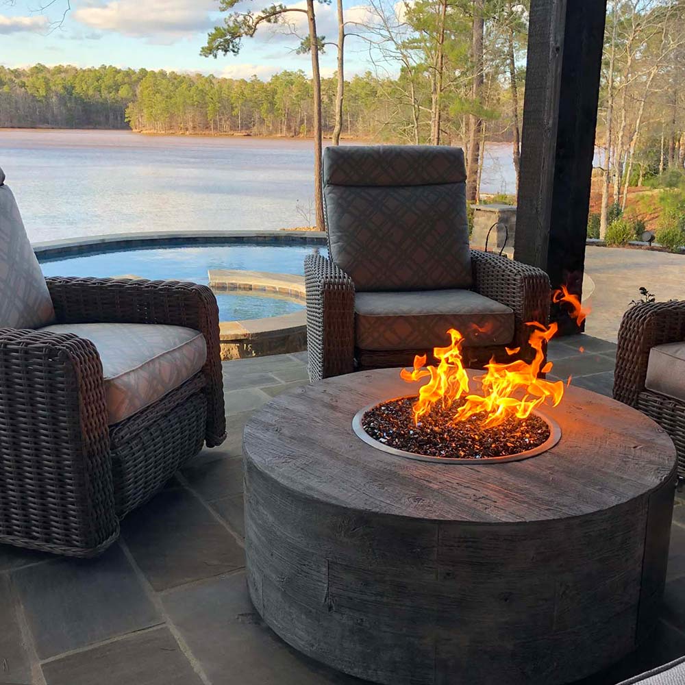 Round wood-grain concrete gas fire pit with burning flames in circular burner