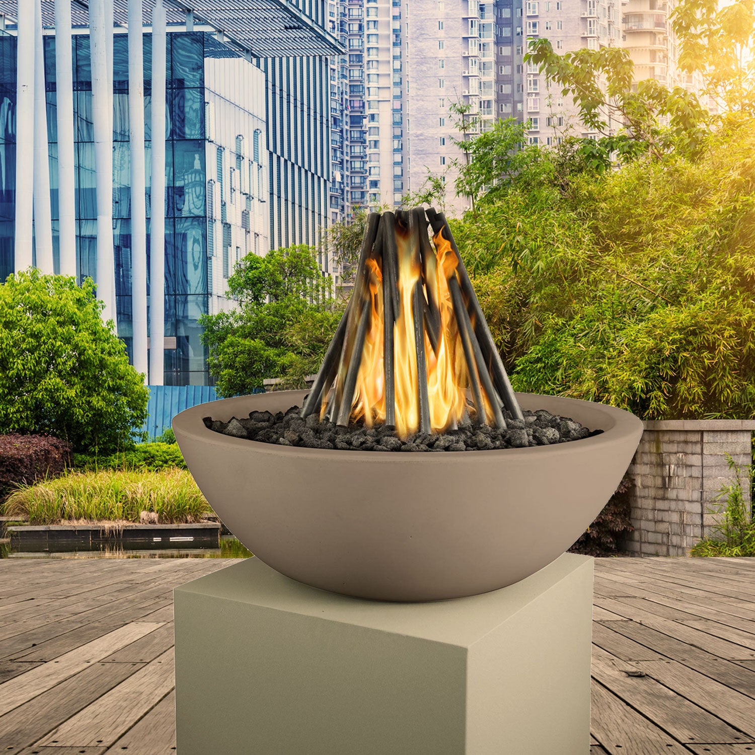 Outdoor fire pit with steel logs and orange flames in round gray bowl
