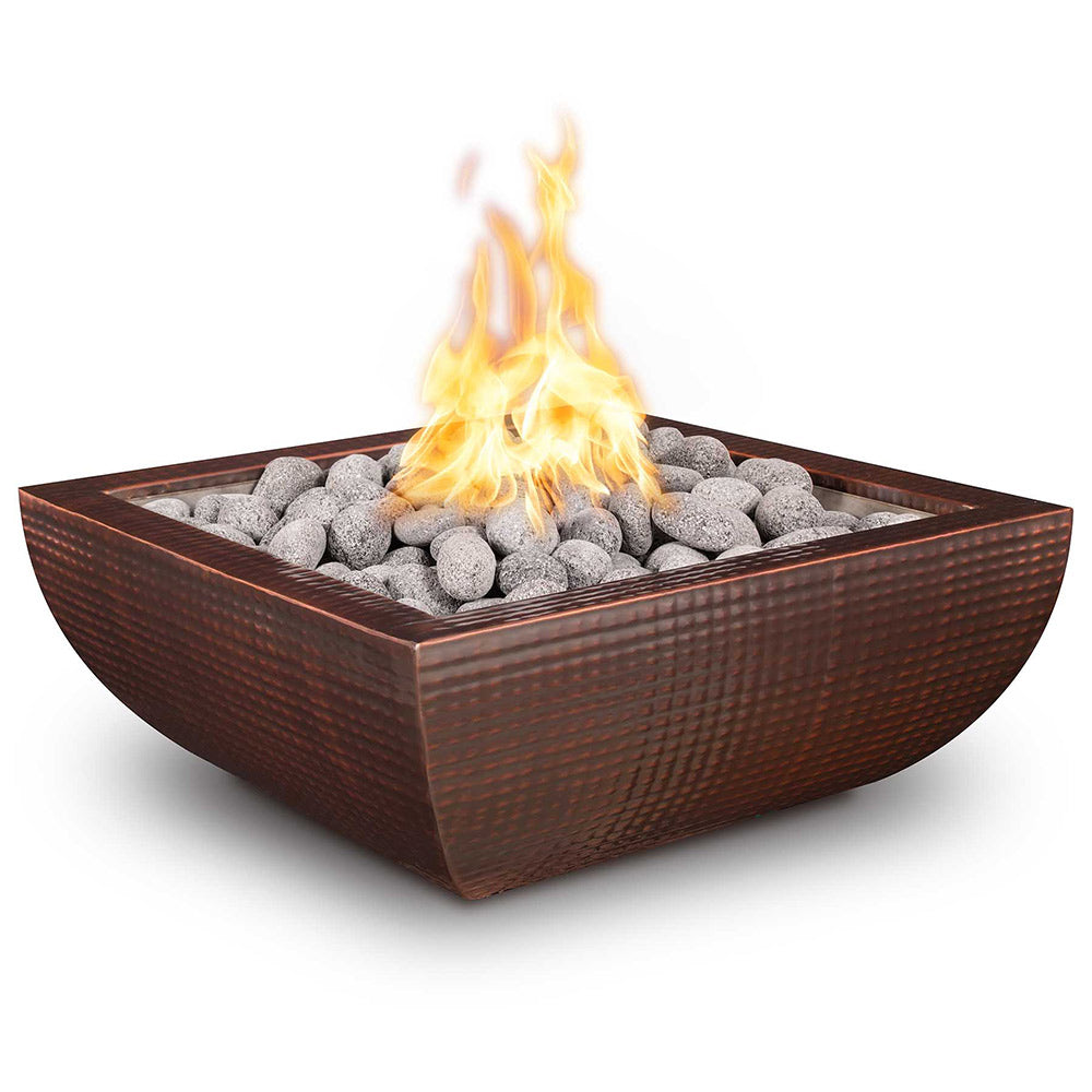 Copper gas fire bowl with glowing flames over gray fire stones