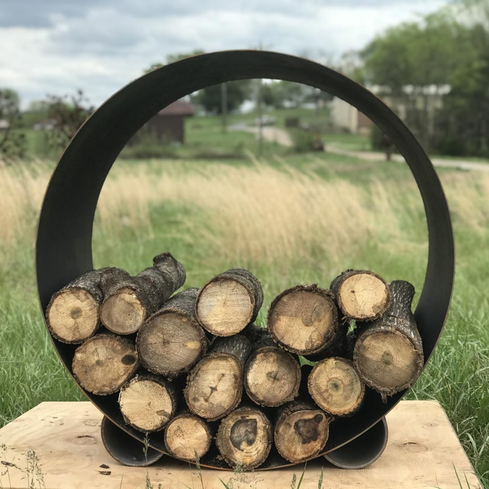 Round steel log rack with black ring handle and dark cut logs