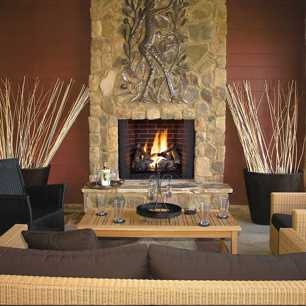 Gas log set in stone fireplace with glowing flames and dark ceramic logs