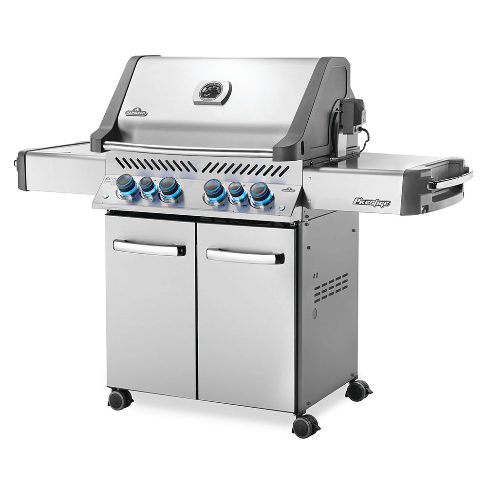 Stainless steel gas grill on cart with lid open, front knobs, and side shelf on right