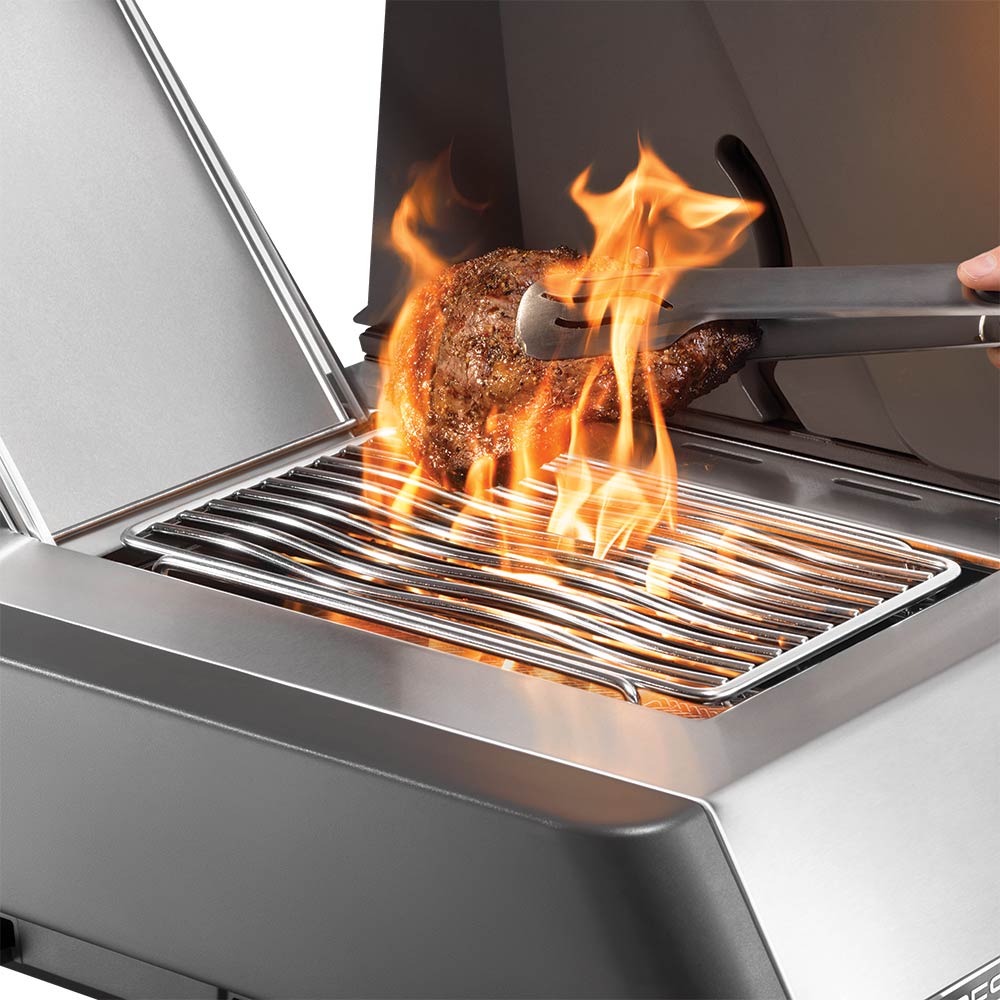 Gas grill infrared searing area with flames and spatula over the grate