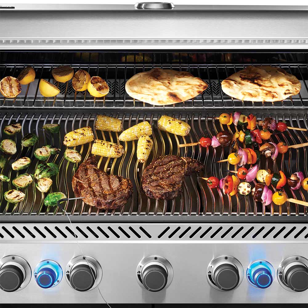 Gas grill cooking grate with pizza slices, vegetables, and seared meats