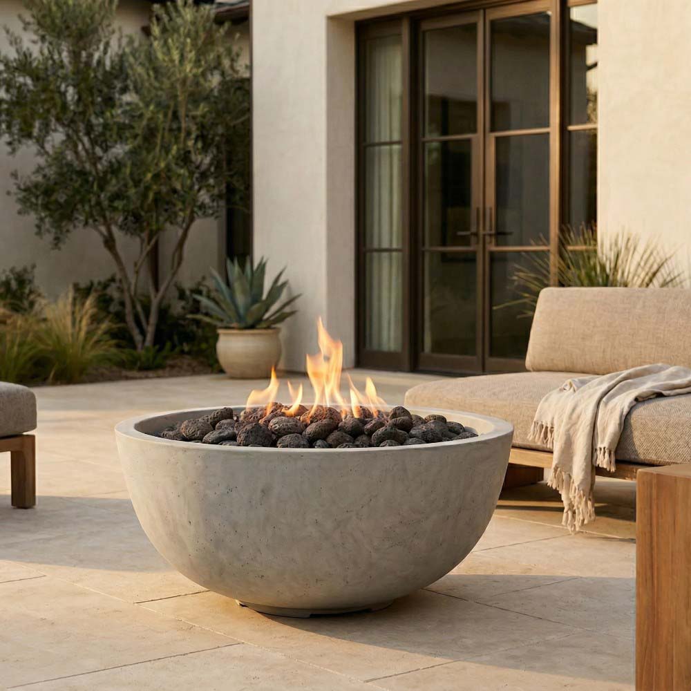 Modern concrete gas fire pit with flames and black lava rocks on patio