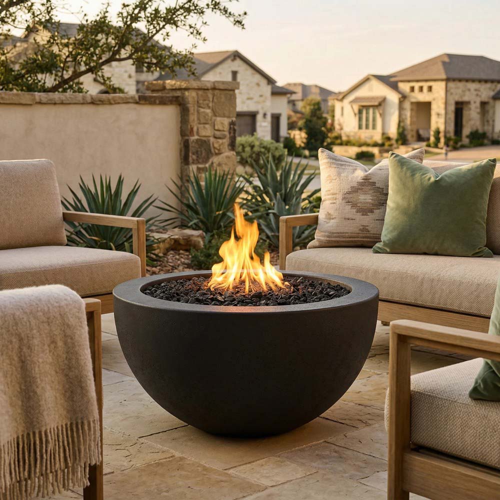 Dark concrete gas fire pit with open flame and black fire glass rocks in bowl