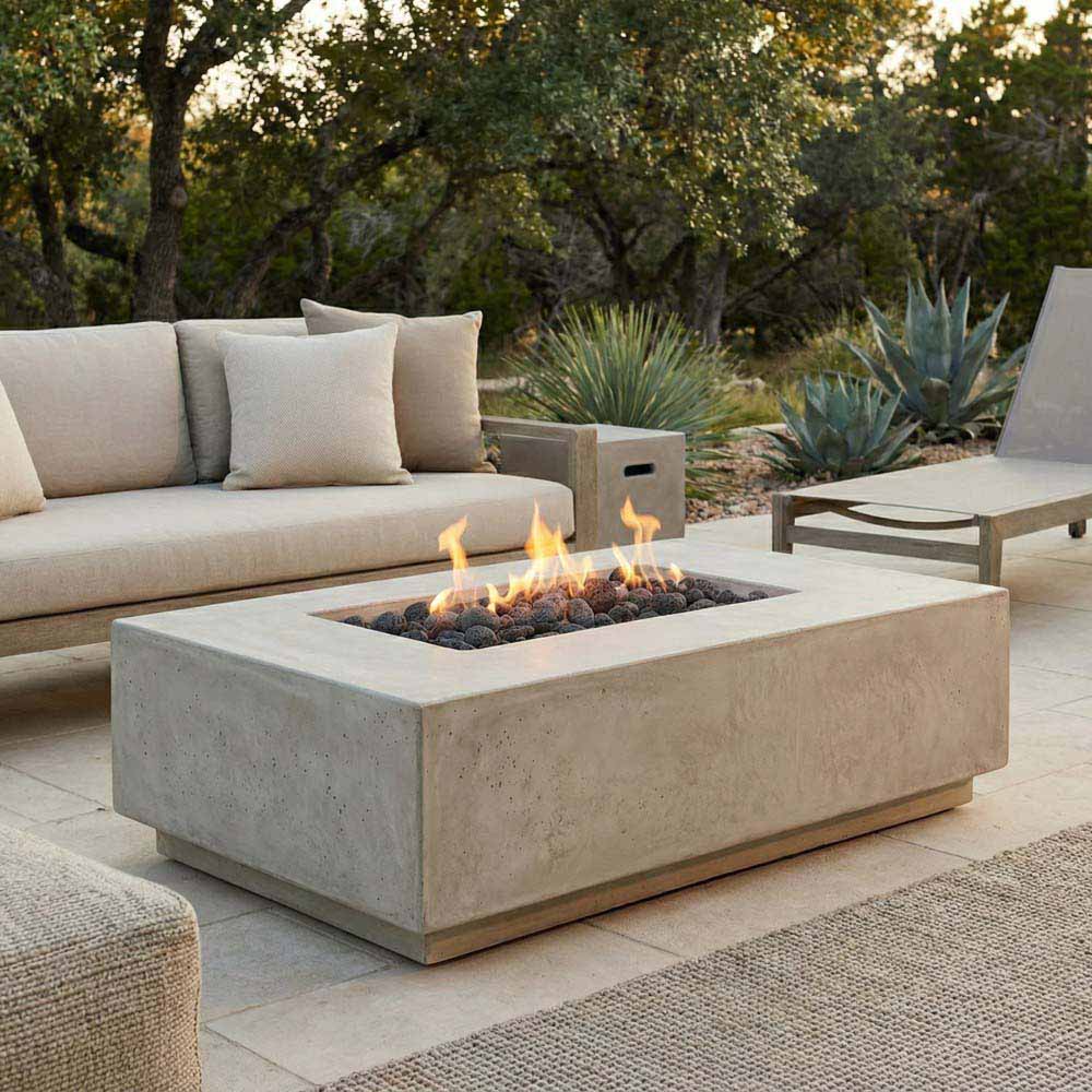 Gray rectangular concrete gas fire pit with visible flames and black lava rock bed