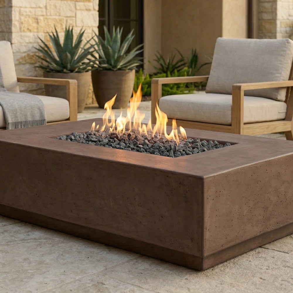 Rectangular concrete gas fire pit with open flame and black lava rocks in the firebox