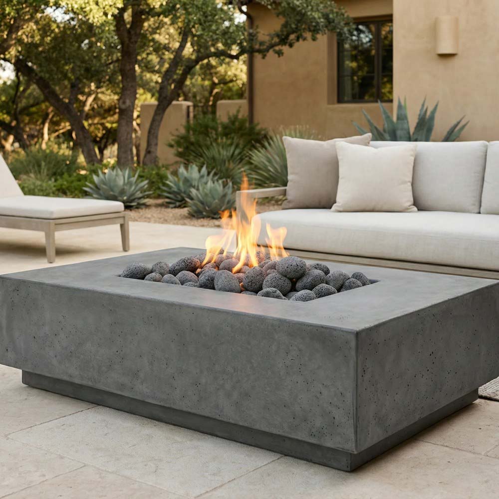 Concrete gas fire pit with rectangular firebox and glowing flames over black lava rocks