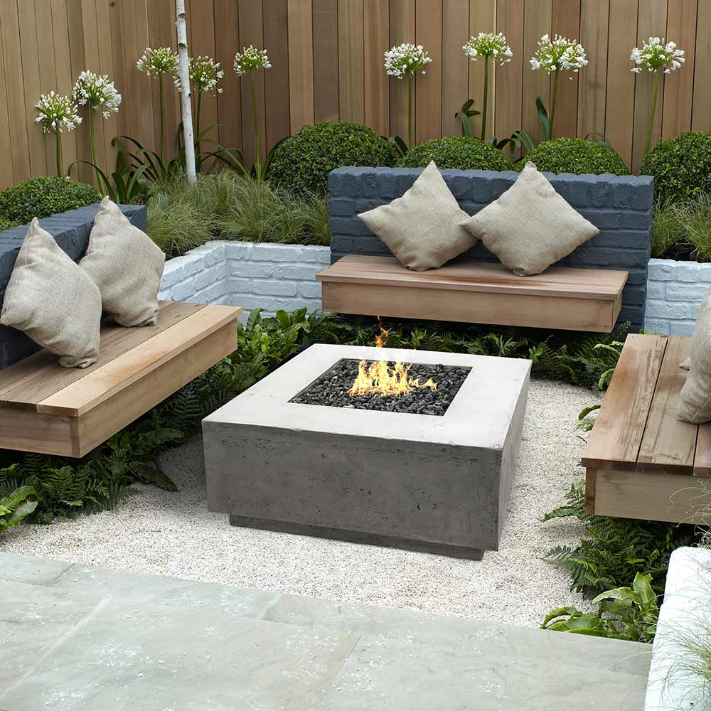 Concrete gas fire pit with visible flame in an outdoor patio seating area