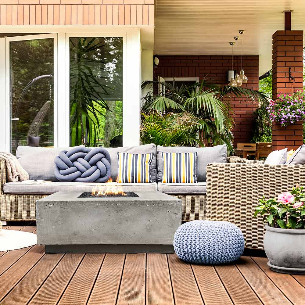 Square concrete gas fire pit with flame on an outdoor patio deck