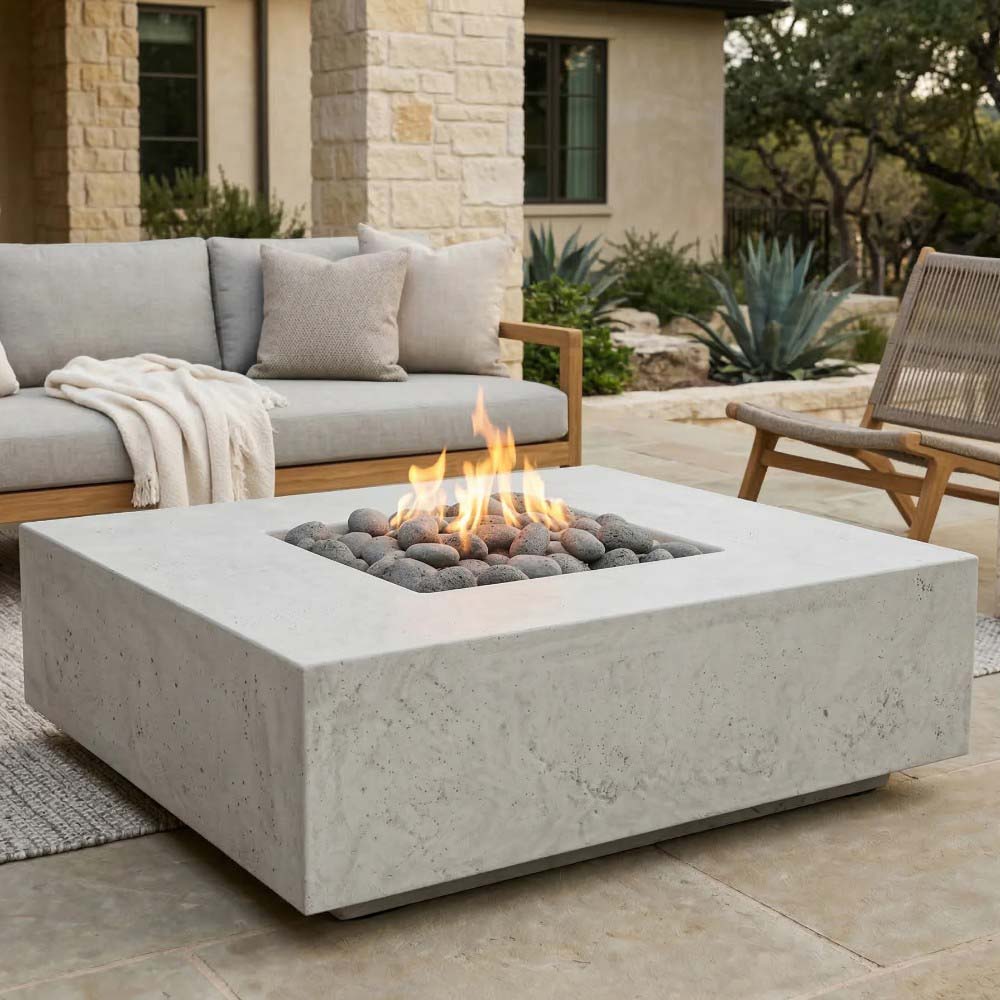 Square concrete gas fire pit with flames and dark lava rocks, light stone finish