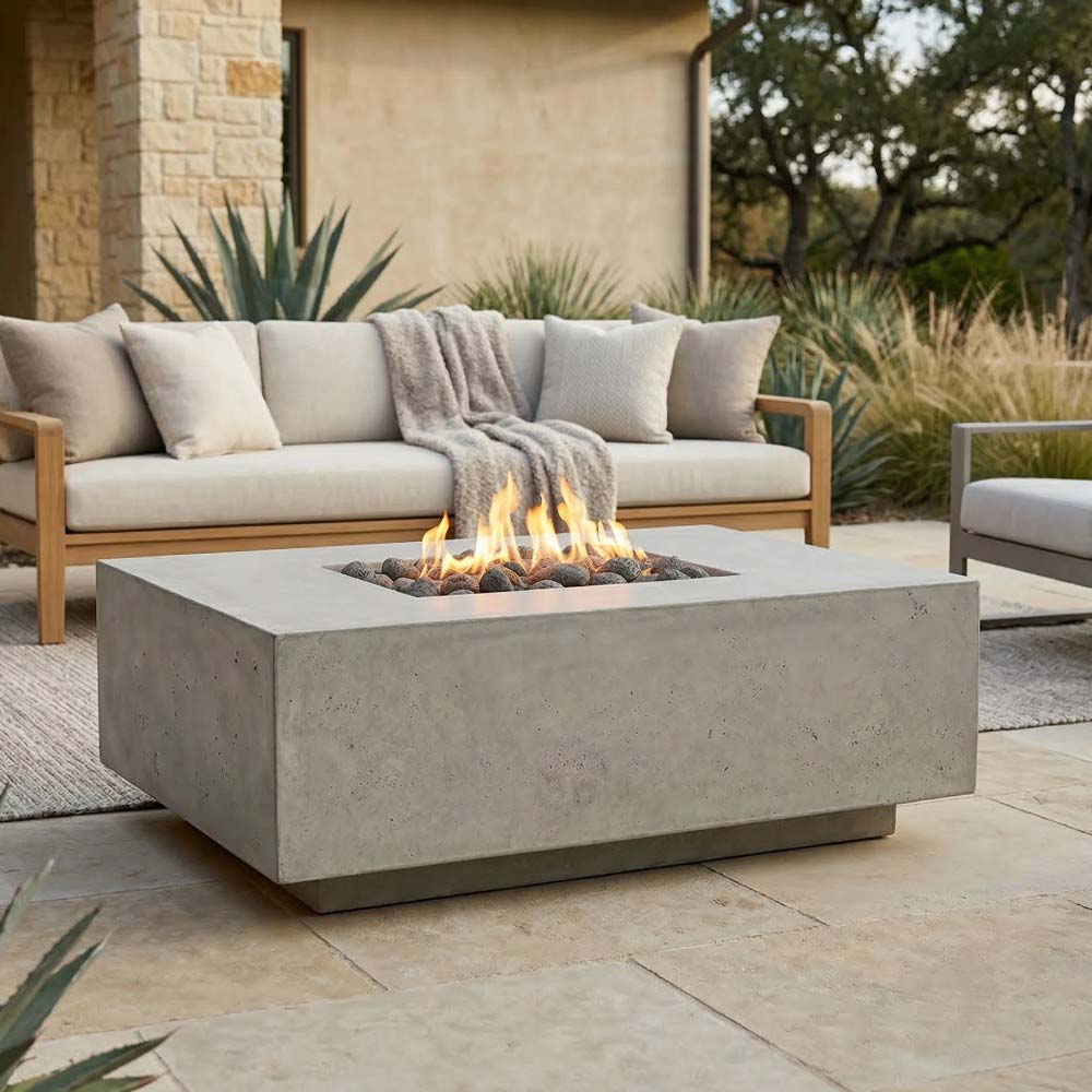 Square concrete gas fire pit with flames over black lava rocks, light concrete finish