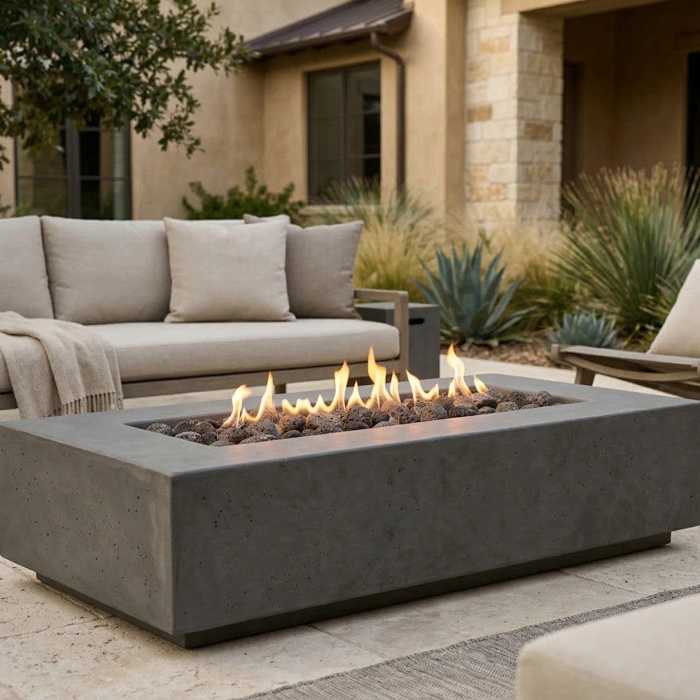 Gray concrete gas fire pit with rectangular firebox and flames on lava rocks