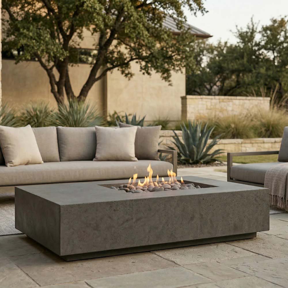 Concrete gas fire pit in dark gray finish with flames, surrounded by outdoor seating