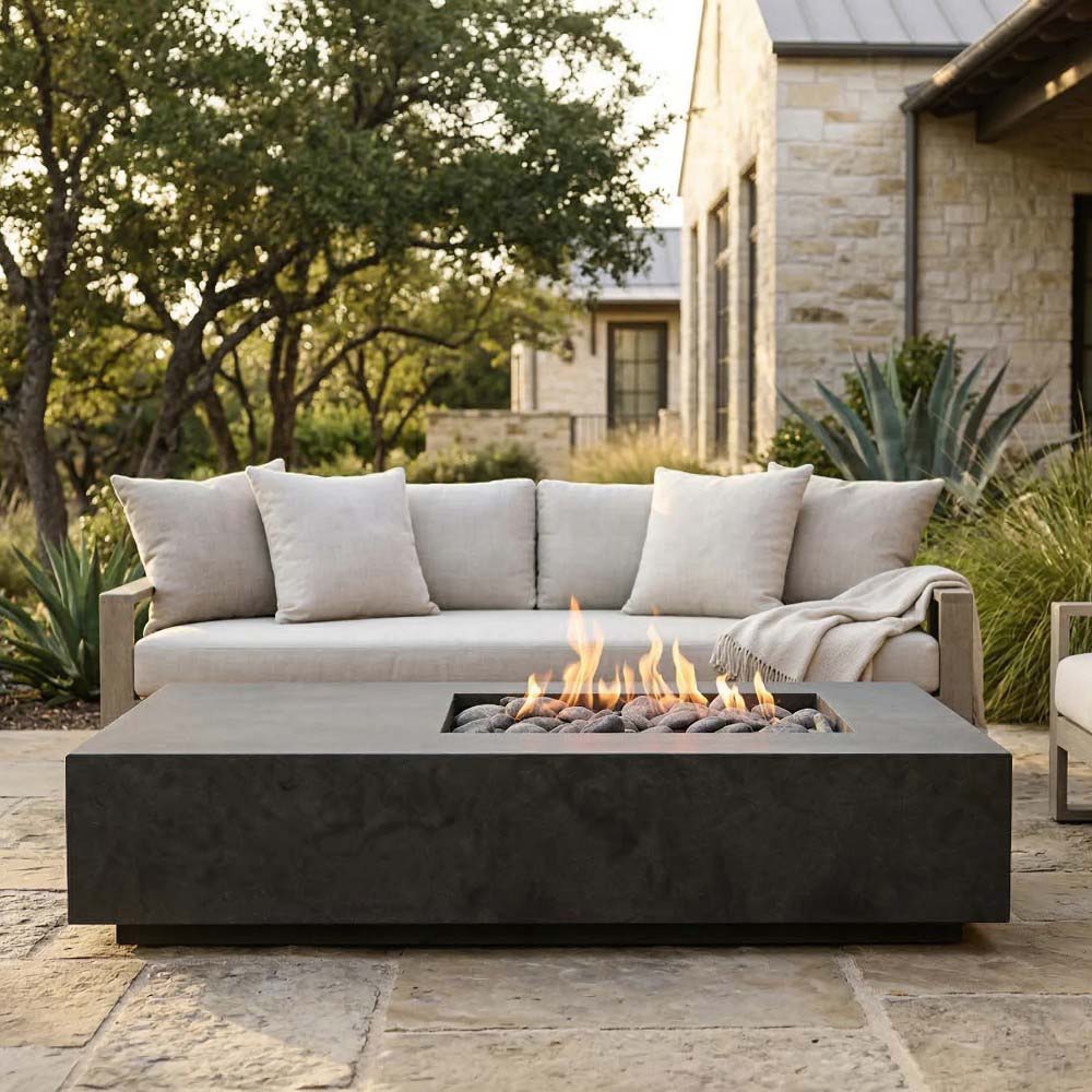Concrete gas fire pit with square firebox and flames, set on patio pavers