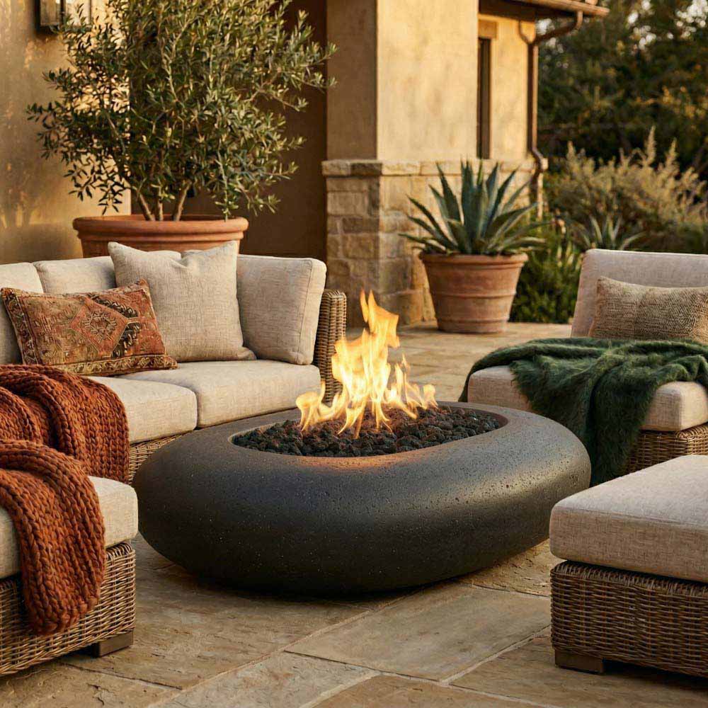 Pebble concrete gas fire pit with flame, rounded dark bowl shape on patio