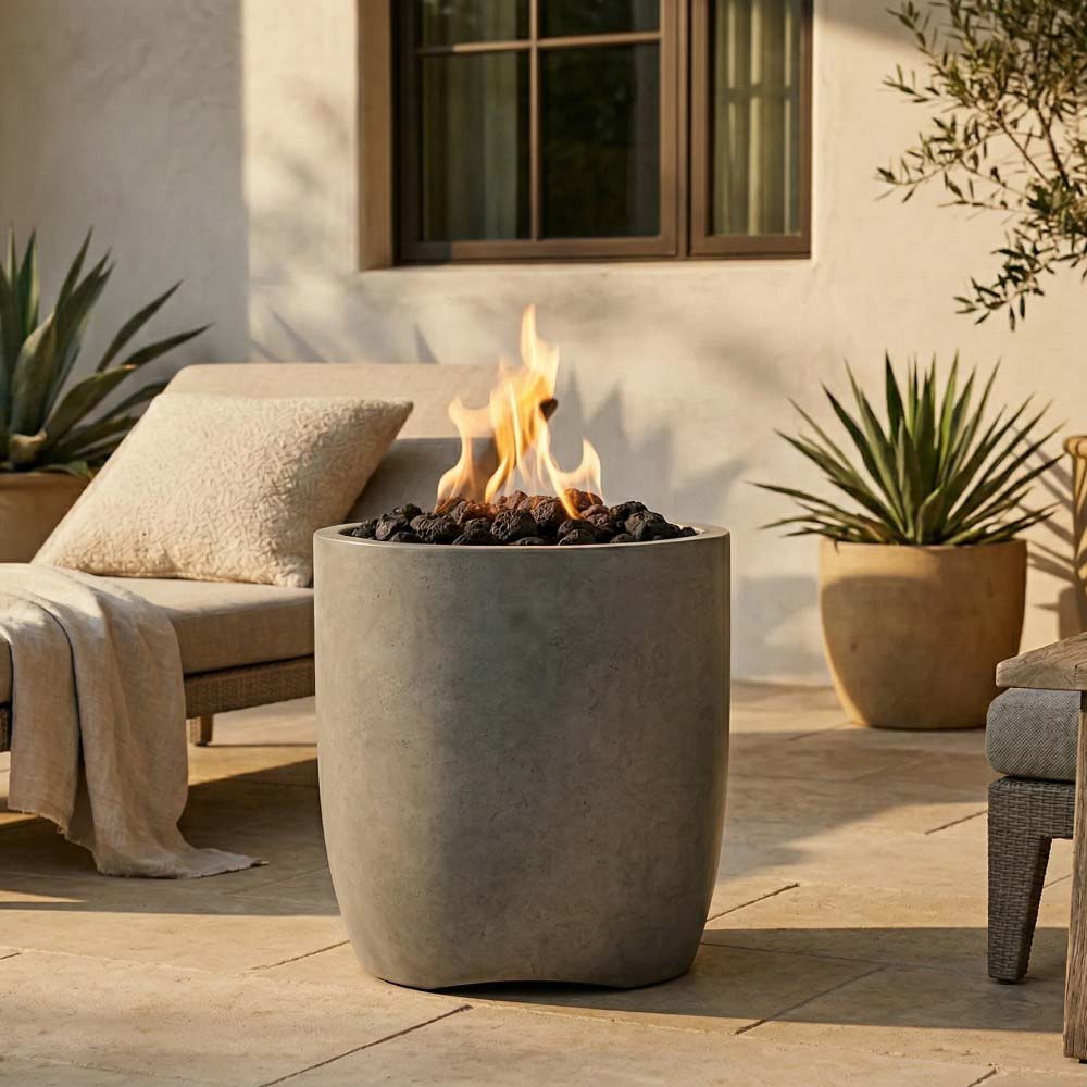 Concrete gas fire pit with flames, light gray bowl on outdoor patio