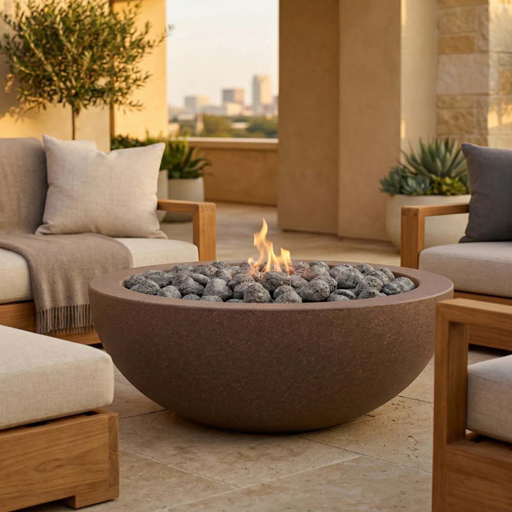 Tan concrete round gas fire pit with flame over dark lava rocks on a patio
