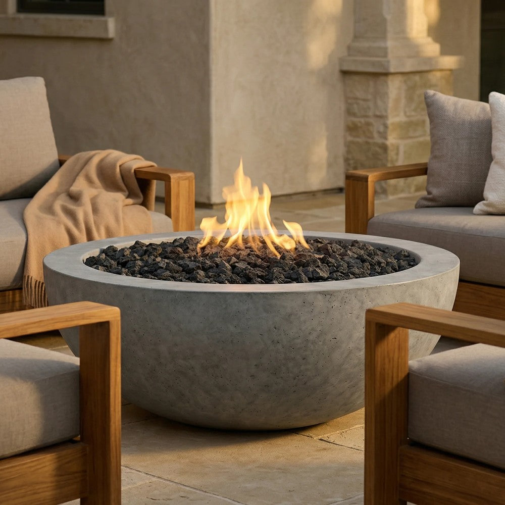 Concrete round gas fire pit with flame, black lava rocks, and pebble-gray finish