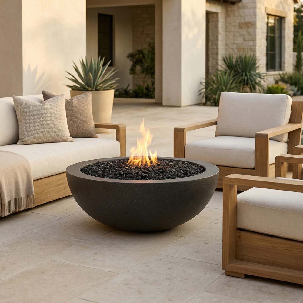 Modern round gas fire pit with fire flame bed and black lava rocks in a patio setting