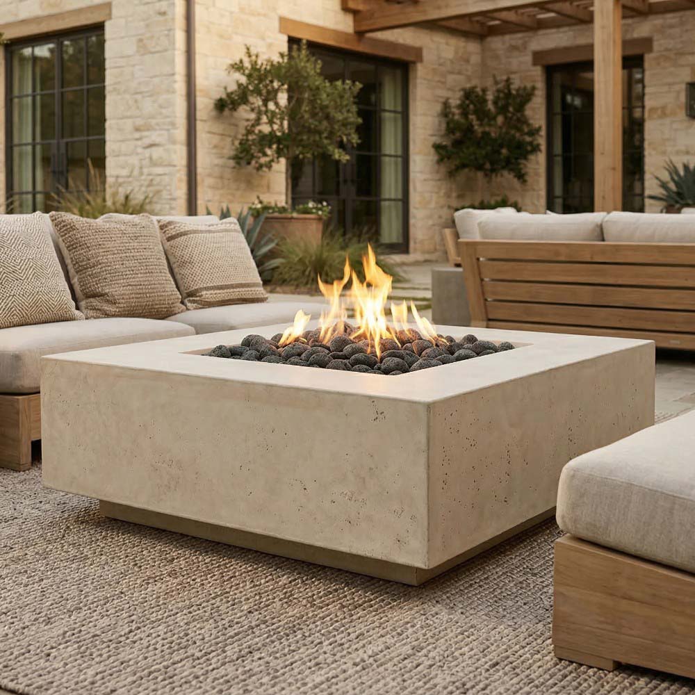 Square concrete gas fire pit with open flame and dark lava rocks in burner pan