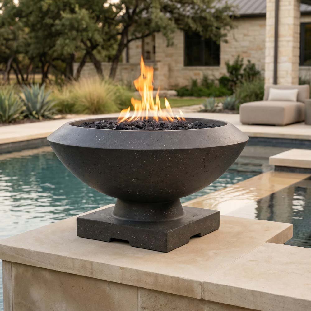 Concrete gas fire bowl in dark gray concrete finish with flames and black lava rock