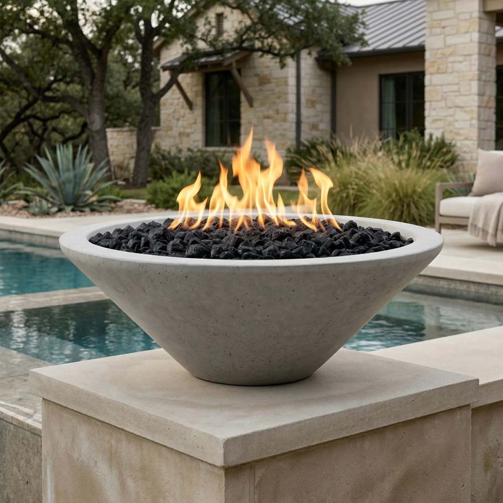 Pedestal concrete gas fire pit with open flame and black lava rocks on display top