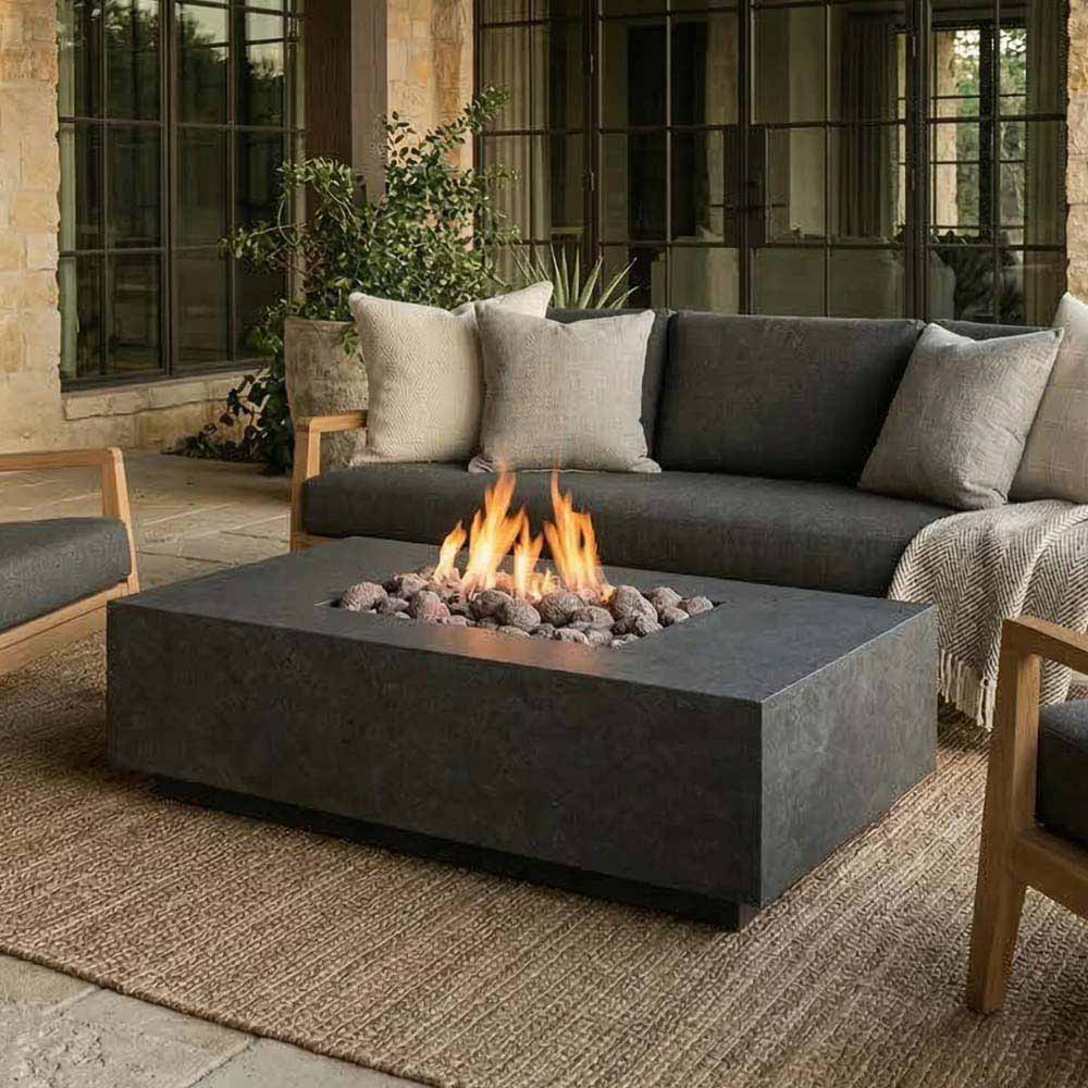 Low rectangular concrete gas fire pit with flames and dark burner media
