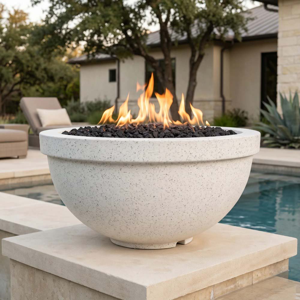 Concrete gas fire bowl with round light stone finish and visible flame above lava rock.