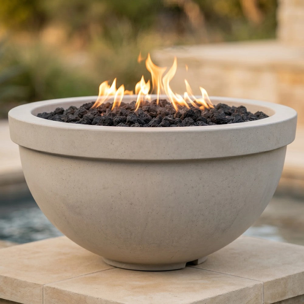 Light concrete gas fire bowl with flame and black lava rock, round rim top.