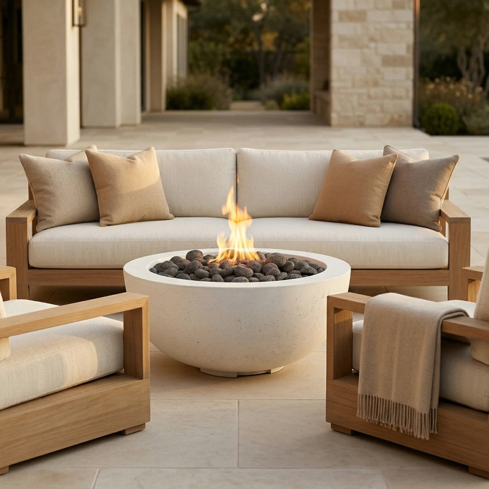 Concrete fire pit bowl with glowing flame and dark lava rocks on outdoor seating patio