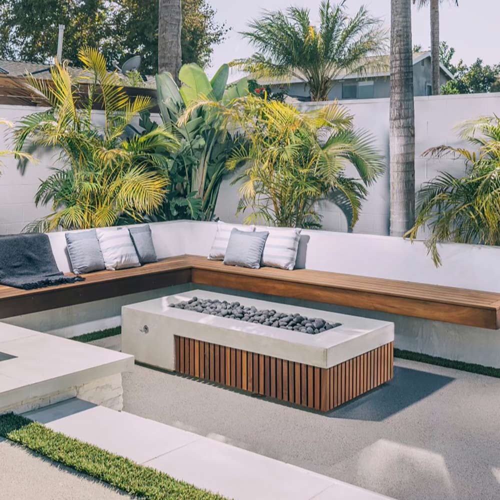 Outdoor concrete gas fire pit with dark wood slats and black lava rocks in square basin