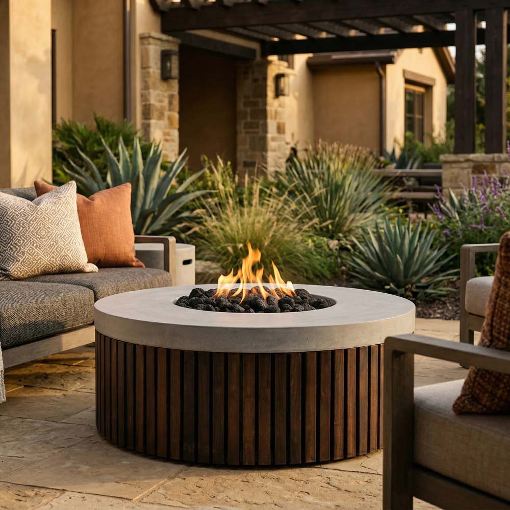 Outdoor round gas fire pit with burning flames, concrete top, and wood-slatted sides